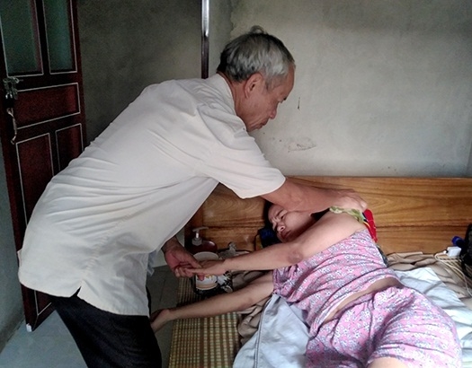 Cựu chiến binh Nguyễn Viết Tiệm chăm sóc người con gái bệnh tật.